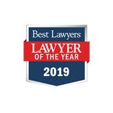 Badge reading "Best Lawyers, Lawyer of the Year 2019" on a blue background with a red banner, symbolizing prestige and recognition.